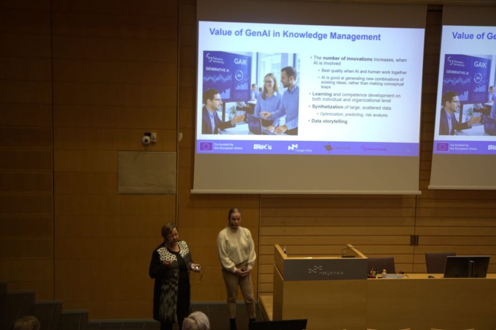 2 women standing in the audiotorium in front of the presentation