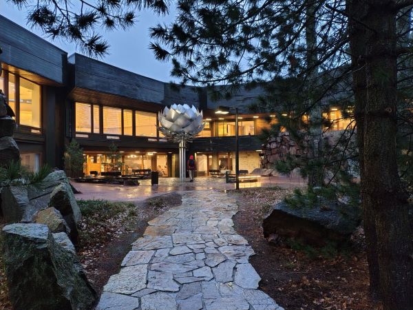 a big silver cone sculpture during night time in front of a building